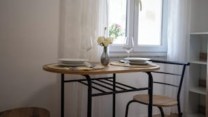 A dining table with plates, cutlery, and a vase with flowers, positioned near a window with curtains. - Comfort Vrsar Apartments (Vrsar)