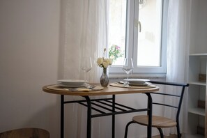 A dining table with plates, cutlery, and a vase with flowers, positioned near a window with curtains. - Comfort Vrsar Apartments (Vrsar)