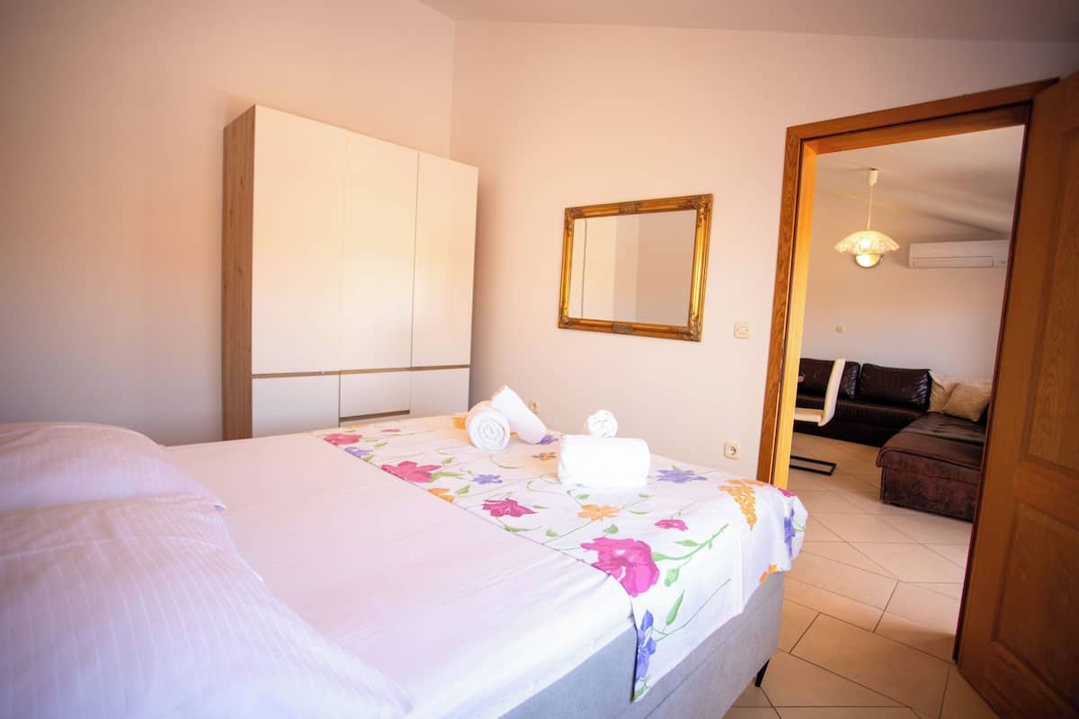 Una camera d'albergo con un letto, un armadio, uno specchio e vista su un'altra stanza.