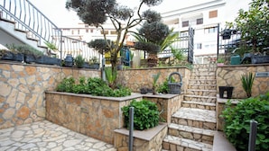 A stone staircase with steps leading up to a landing, surrounded by greenery and potted plants. - Comfort Vrsar Apartments (Vrsar)
