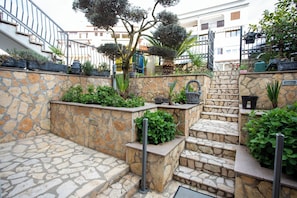 A stone staircase with steps leading up to a landing, surrounded by greenery and potted plants. - Comfort Vrsar Apartments (Vrsar)