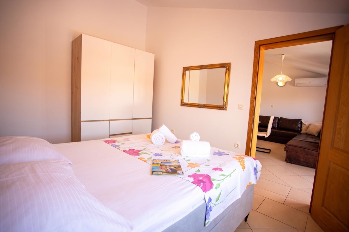 A hotel room with a bed, a wardrobe, a mirror, and a bathroom visible through an open door.