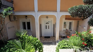A courtyard with a stone pathway, a white door, and potted plants. - Comfort Vrsar Apartments (Vrsar)