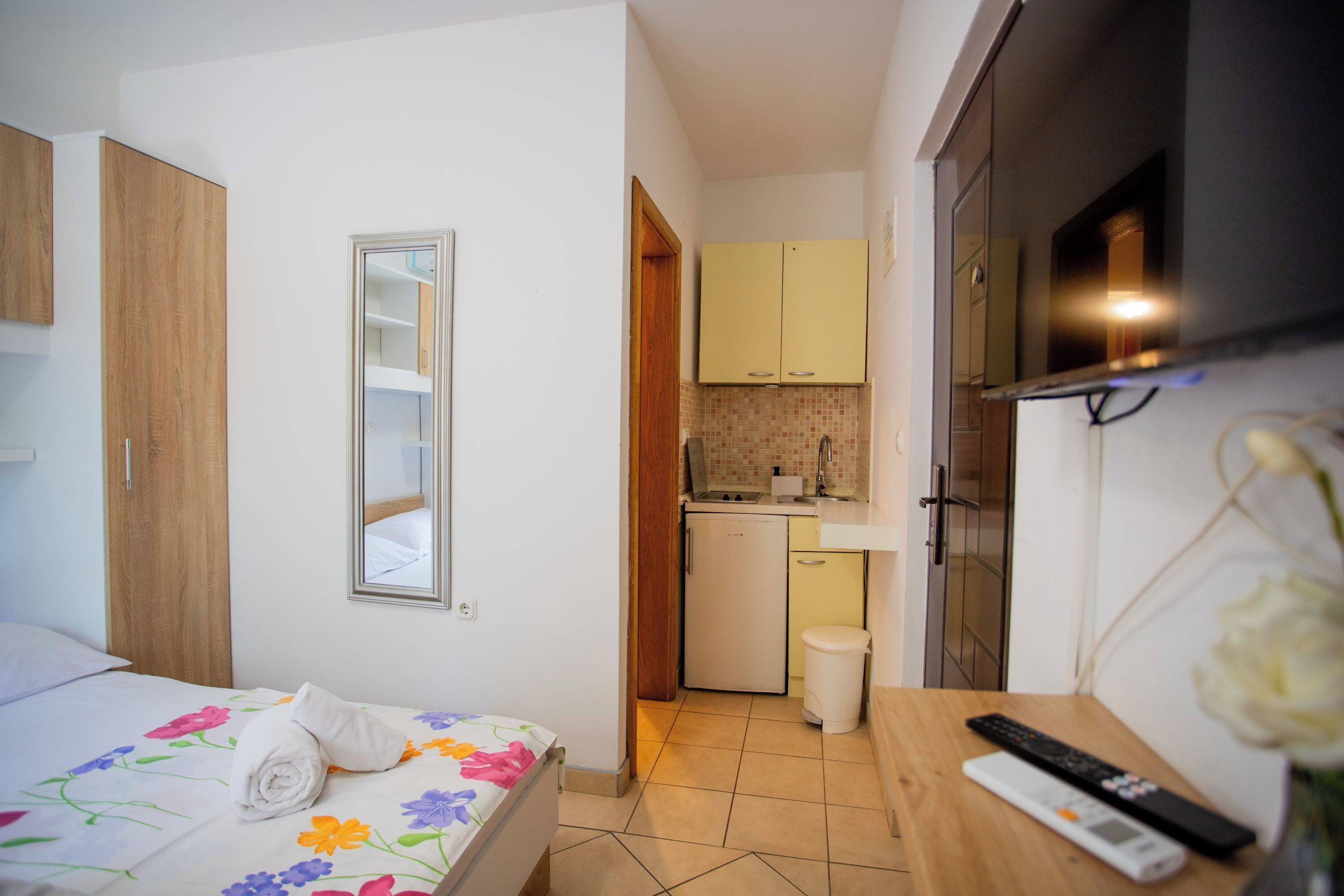 Una habitación de hotel con cama, una kitchenette pequeña, un televisor y baño.