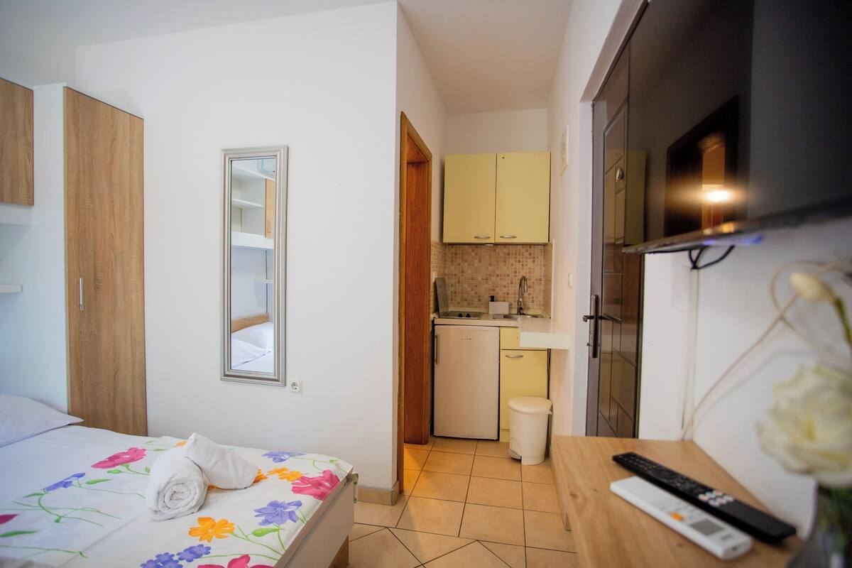 Una camera d'albergo con un letto, un angolo cottura, una televisione e un bagno.