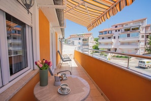 A balcony with a table, chairs, a vase with flowers, and a view of buildings. - Comfort Vrsar Apartments (Vrsar)