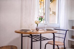 A dining table with plates, glasses, and a vase with flowers, set against a window with curtains. - Comfort Vrsar Apartments (Vrsar)