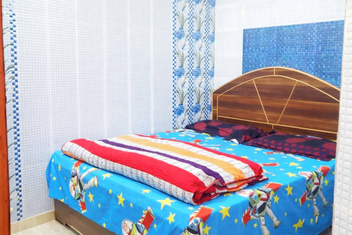 A bedroom with a bed, curtains, and a blue wall with a pattern.