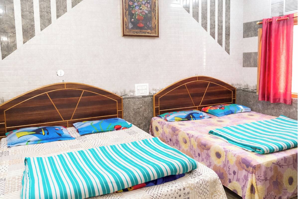 A hotel room with two beds, a wooden headboard, a floral painting on the wall, and a red curtain.