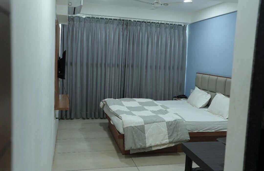 A bedroom with a bed, a bedside table, a curtain, and a ceiling fan.