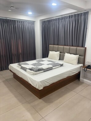 Ein Schlafzimmer mit Bett, Vorhängen, Nachttisch und Telefon.