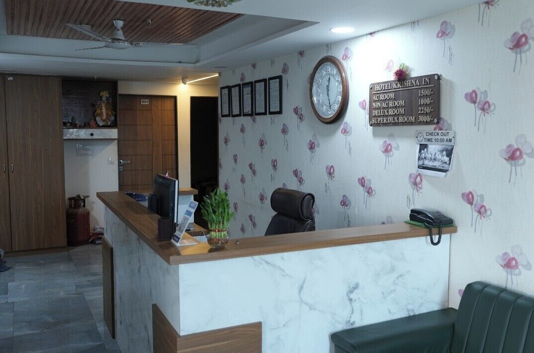 Un'area della reception di un hotel, con una scrivania, un orologio e una parete con informazioni sulle camere.