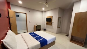 A hotel room with a bed, a desk, a chair, a television, and a wardrobe. - Surbhi Grant (Khatoo)