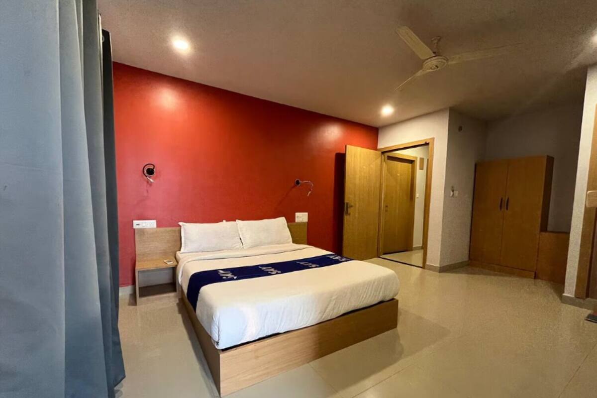 A bedroom with a bed, a wardrobe, a door, and a ceiling fan.