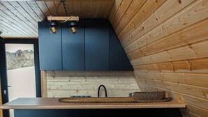 Een moderne keuken met een houten inrichting, twee zwarte barkrukken en een houten aanrecht.