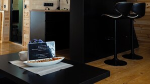 Een moderne keuken met houten wanden, een zwart aanrecht en een zwarte barstoel.