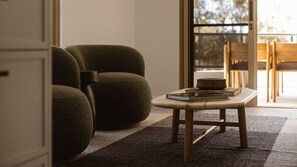 Ein Zimmer mit einer Couch, einem kleinen Tisch mit Büchern und Blick durch eine Glastür.