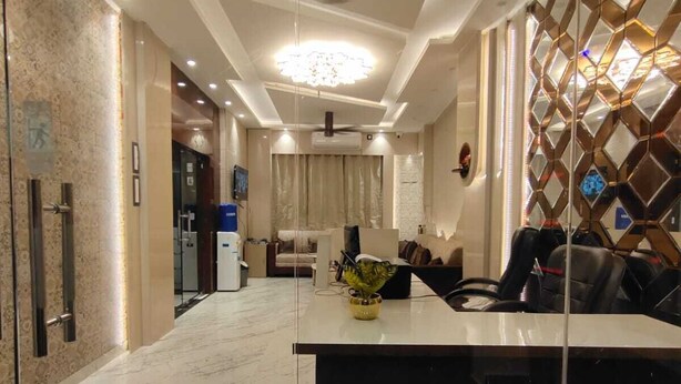A modern hotel lobby with a marble floor, a reception desk, a chandelier, and a seating area with a sofa and chairs. -  Shri Khatu Shyam Residency (Varanasi)