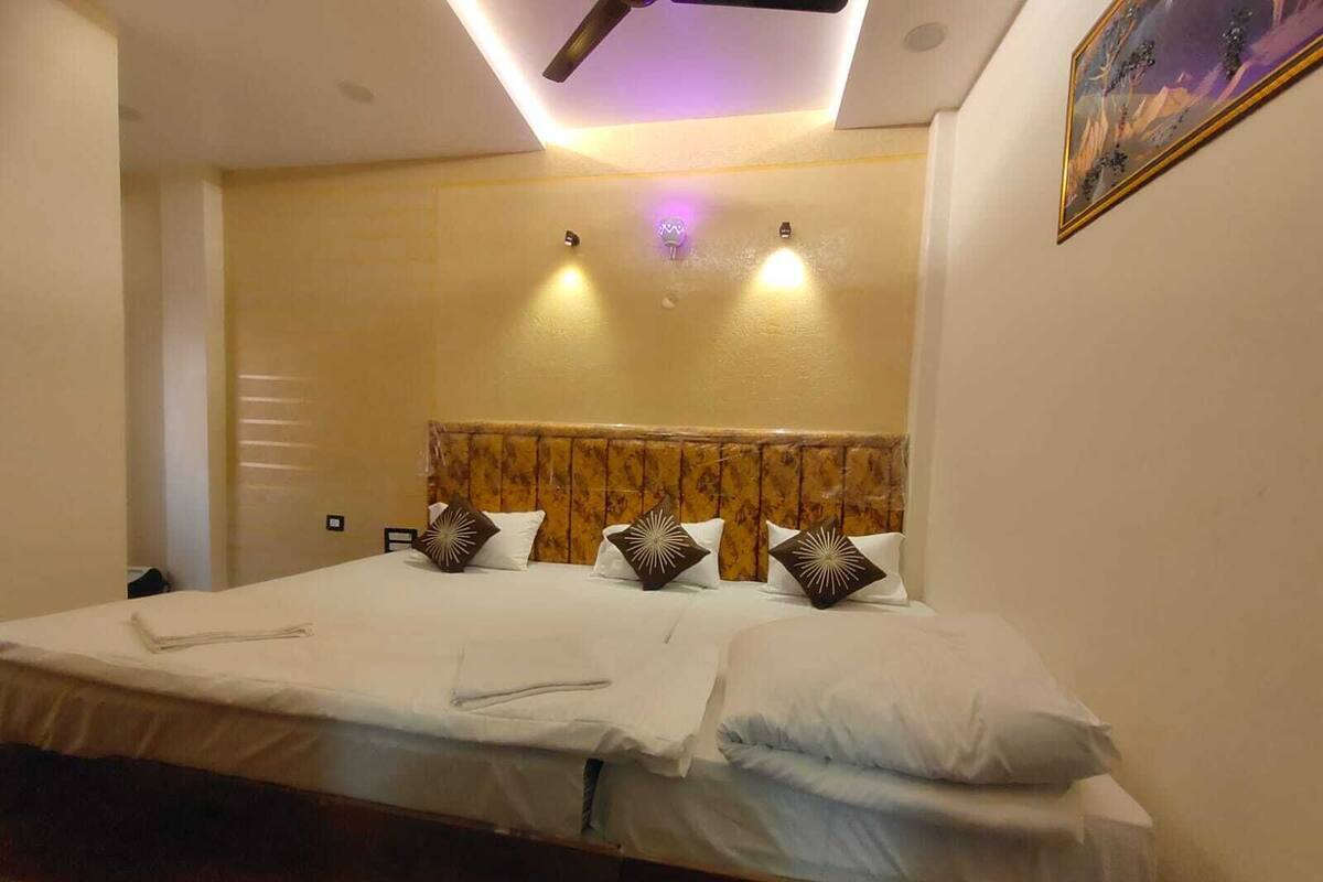 A hotel room with a bed, a ceiling fan, recessed lighting, and a painting on the wall.