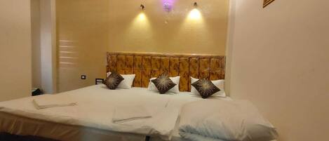 A hotel room with a bed, a ceiling fan, recessed lighting, and a painting on the wall.