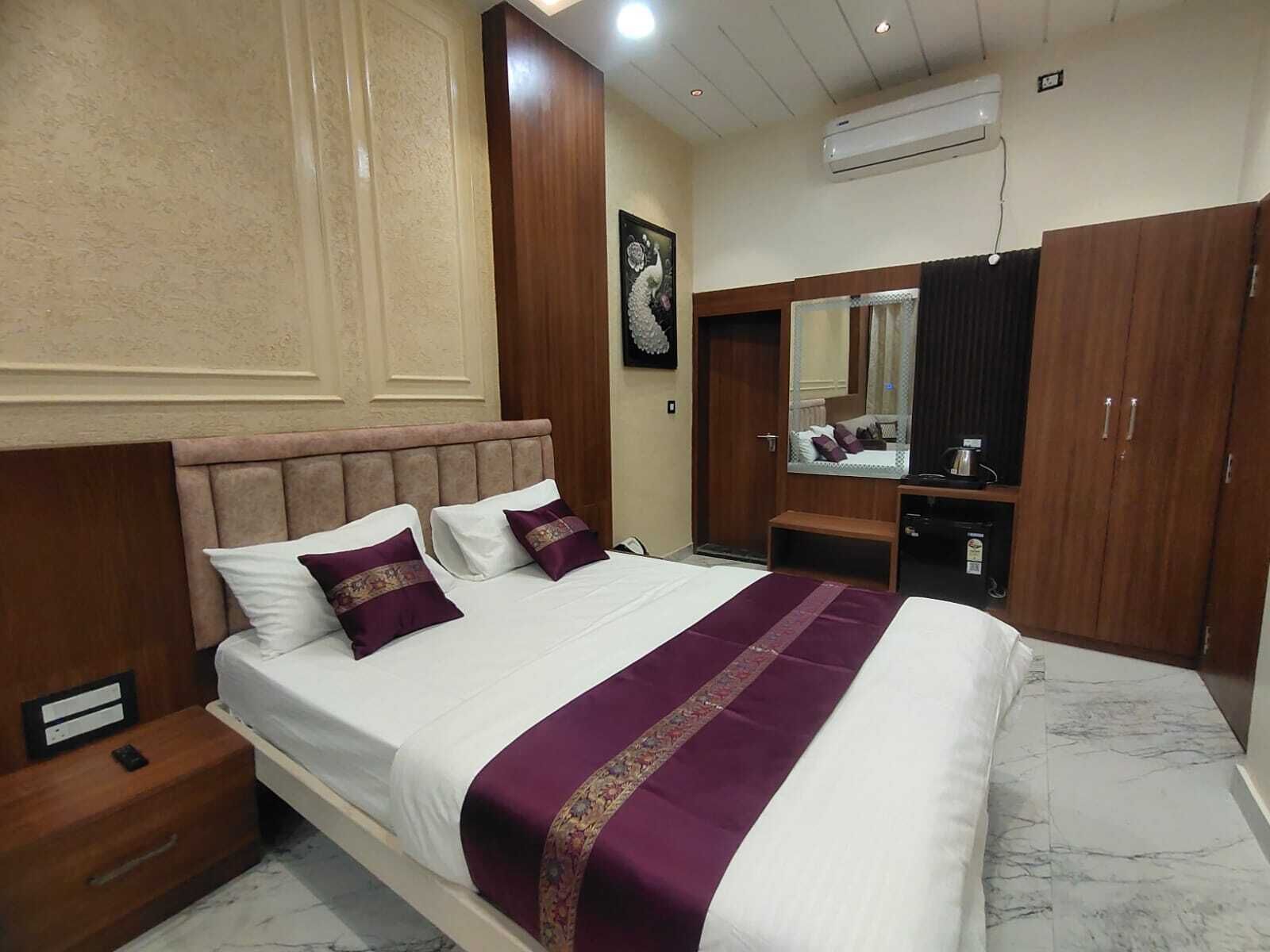 Una camera d'albergo con un letto, un comodino, un armadio, uno specchio e un condizionatore d'aria.