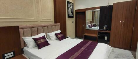 A hotel room with a bed, nightstand, wardrobe, mirror, and an air conditioning unit.