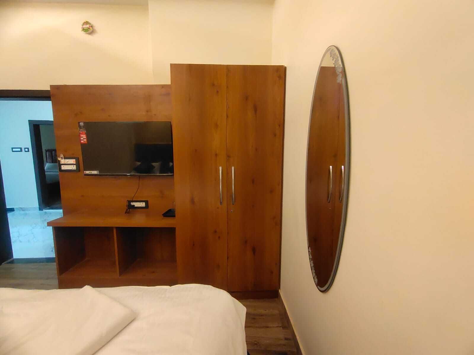 A bedroom with a bed, wooden wardrobe, and a large mirror.