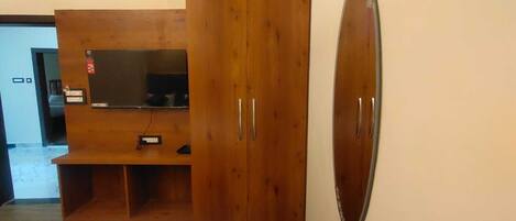 A bedroom with a bed, wooden wardrobe, and a large mirror.