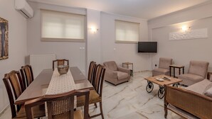 A dining area with a table, chairs, and a television in the background. - Marina Zeas Hidden Gem (Pireas)