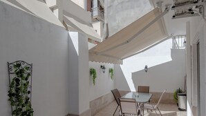 A patio with a table and chairs, a hanging plant, and a tiled floor. - Marina Zeas Hidden Gem (Pireas)
