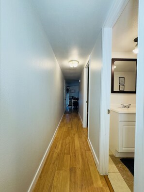 A hallway with wooden flooring, white walls, and a ceiling light fixture. - Cabin 7 2-bedroom house along the Gasconade River on a lovely Campground Resort (Richland)