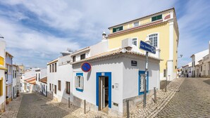 Una calle empedrada con edificios, una señal de 'prohibido estacionar' y una señal que indica 'Rua do Couto de Mouta'.