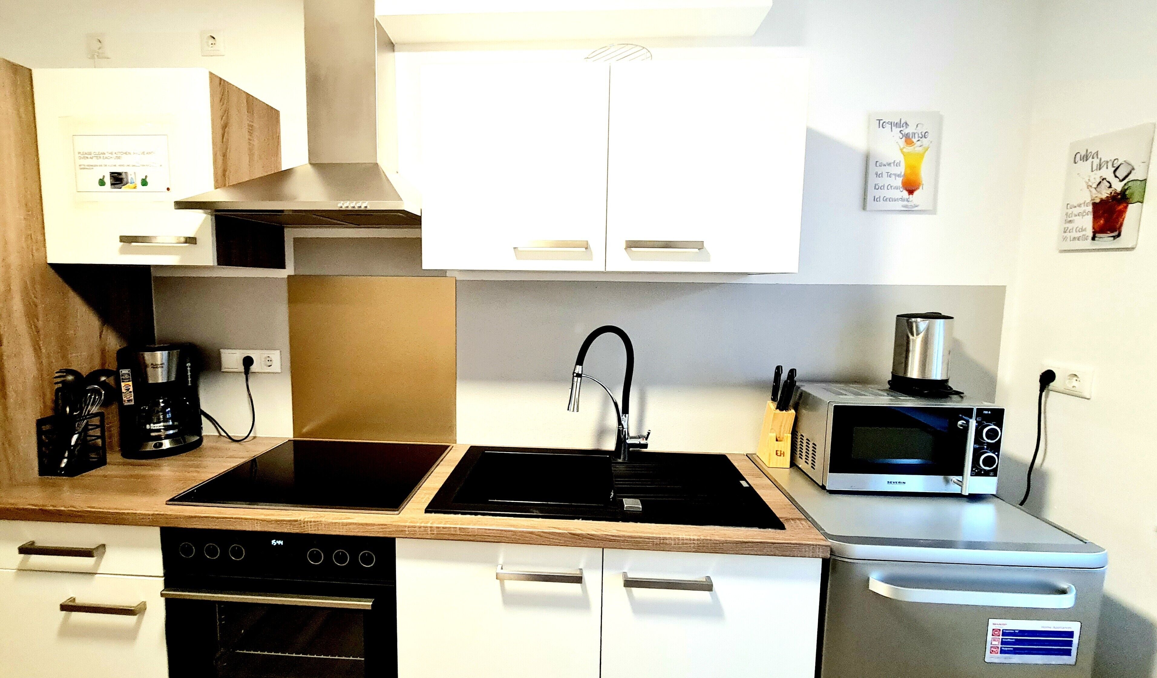 Eine moderne Küche mit Herd, Backofen, Mikrowelle und Kaffeemaschine.