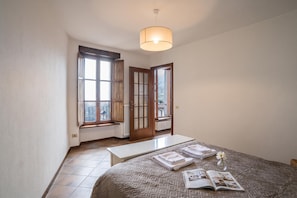 A bedroom with a bed, a bedside table, a window, and a door. - Casa Tranquillita Lario (Plesio)