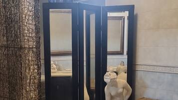 A bathroom with a marble sink, a statue, and a mirror.