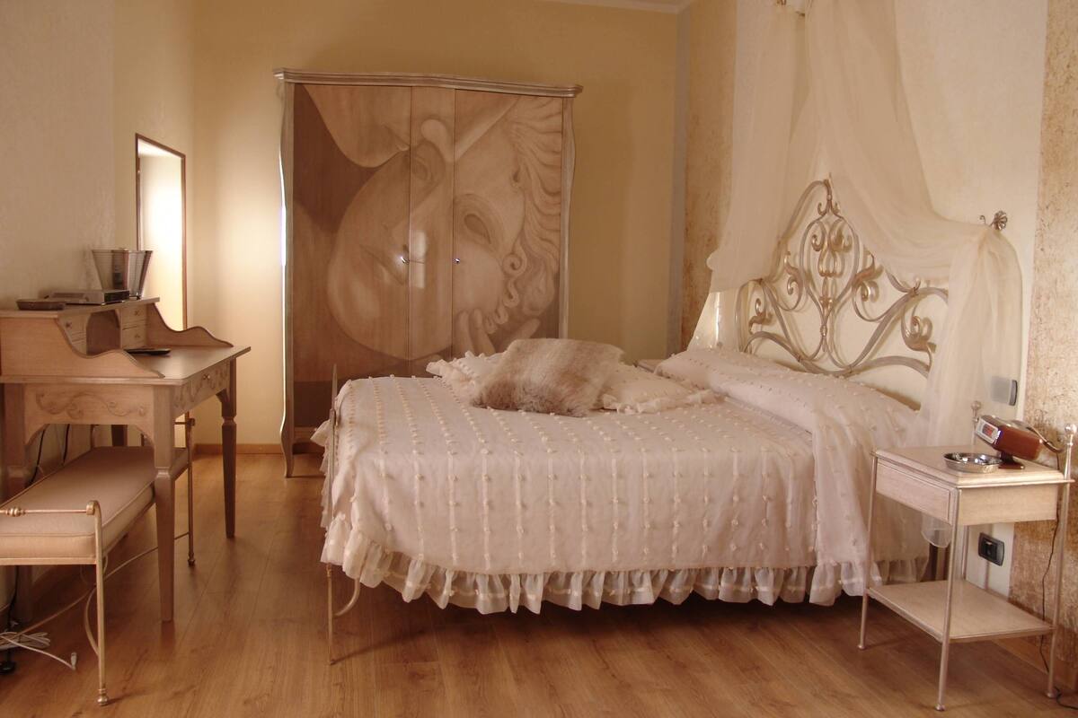 A bedroom with a bed, a desk, and a wardrobe.