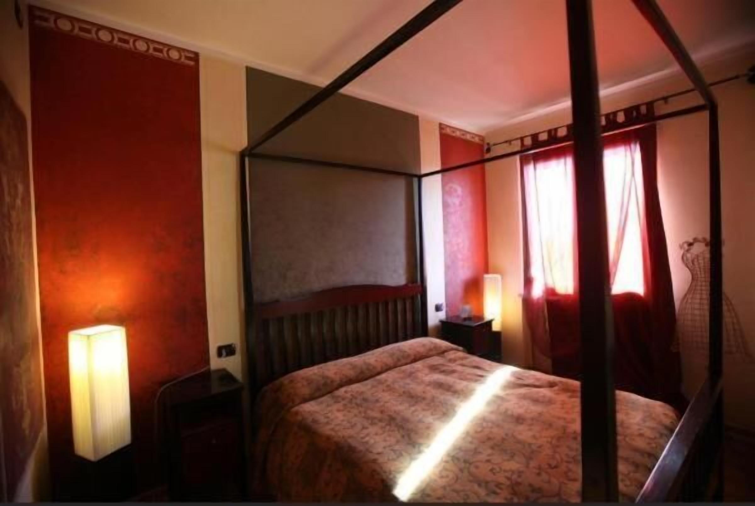 Un lit à baldaquin avec une tête de lit, une table de chevet avec une lampe et une fenêtre avec des rideaux.