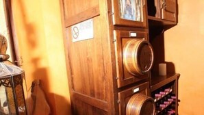 A wooden cabinet with wine bottles, a bowl, and a guitar in a room with orange walls. - Manuela Quattro Coppe (San Martino della Battaglia)