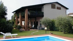 A swimming pool with lounge chairs, a house with a balcony, and a well-maintained lawn. - Manuela Quattro Coppe (San Martino della Battaglia)