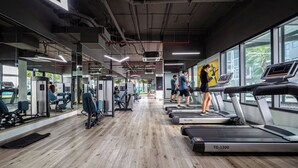 Un gimnasio con cintas de correr, equipo de ejercicio y ventanas amplias.