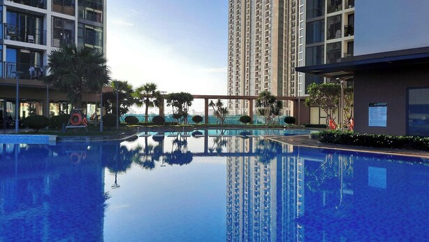Una piscina con agua cristalina, rodeada de edificios modernos y palmeras.