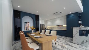 Un comedor moderno con piso de mármol, una mesa de madera y sillas blancas tapizadas.