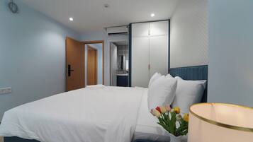 A hotel room with a bed, a nightstand, a lamp, and a vase with flowers.