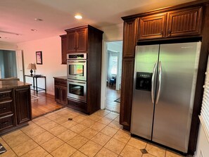 A kitchen with wooden cabinets, a stainless steel refrigerator, and a built-in oven. - West Augusta House (Augusta)
