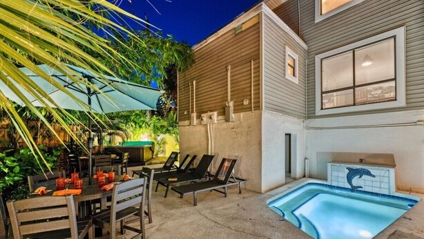 A pool area with lounge chairs, a dining table with chairs, and a small hot tub. - Villa Fiesta - 312   “Siesta Key” (Sarasota)