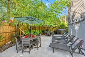 Un patio con mobiliario exterior, una mesa con bebidas y un jacuzzi.
