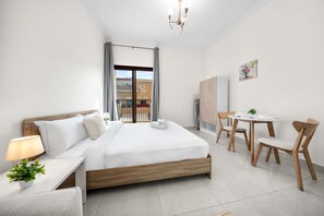 A modern hotel room with a bed, bedside table, lamp, potted plant, and a view of the outside. - Free Housekeeping Visits During Your Stay - Stayshort - Comfortable Studio in JVC That Sleeps 2 (Dubai)