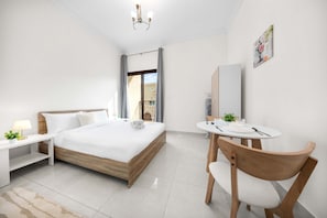A modern hotel room with a bed, bedside table, chair, and a small dining area. - Free Housekeeping Visits During Your Stay - Stayshort - Comfortable Studio in JVC That Sleeps 2 (Dubai)