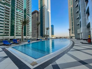 A swimming pool with lounge chairs, surrounded by high-rise buildings. - Free Housekeeping Visits During Your Stay - Stayshort - Bright 1 Bedroom Retreat in Dubai Marina That Sleeps 4 (Dubai)