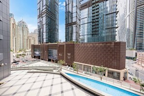 A modern building with a swimming pool, high-rise buildings, and a paved area. - Free Housekeeping Visits During Your Stay - Stayshort - Bright 1 Bedroom Retreat in Dubai Marina That Sleeps 4 (Dubai)